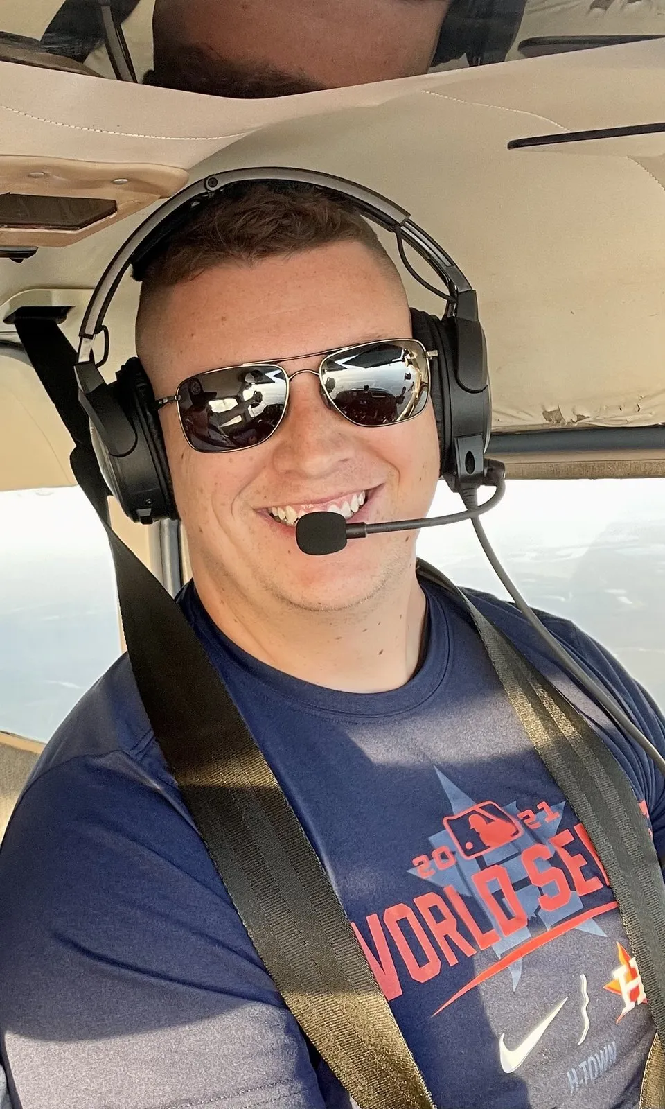 Brandon in the left seat of a small plane, headset on, smiling